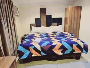a bed with a colorful quilt on it in a room at Summer Breeze Guest House in Suru Lere
