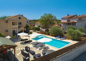 a swimming pool with chairs and umbrellas next to a building at Apartments Borghetto in Vinkuran