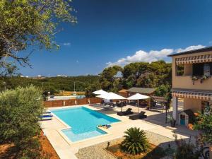 an outdoor swimming pool with umbrellas and a building at Apartments Borghetto in Vinkuran