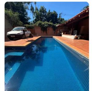a swimming pool with a car parked next to a house at Recanto da harmonia in Ribeirão Preto