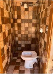 a bathroom with a toilet and a tiled wall at Recanto da harmonia in Ribeirão Preto