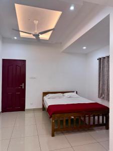 a bedroom with a bed and a red door at Aira Residency in Vennikulam