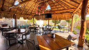 a restaurant with tables and chairs under a straw roof at Hotel y Beach Club Casa Mia Xulha -Bacalar in Xul-Ha