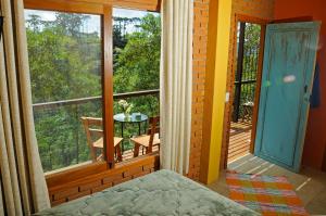 a room with a bed and a balcony with a table at Estalagem Terramauá in Visconde De Maua