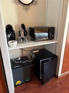 a kitchen with a microwave and a coffee maker on a shelf at Chambre Victory in Colleville-sur-Mer
