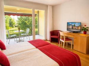 a bedroom with a bed and a desk and a balcony at Parkhotel Emmaus - Casa del Sole in Ascona