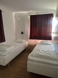 two beds in a room with a red curtain at Svalsjöns Stugor Öland in Köpingsvik