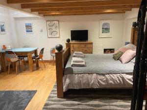 a bedroom with a bed and a table and a television at Tredrea Annexe - Self Contained Cornish hideaway in Truro