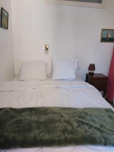 a bed with white sheets and a green blanket on it at Maison Quebec in Bernières-sur-Mer
