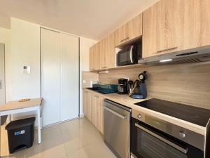 a kitchen with wooden cabinets and a stove top oven at A 150m de la plage - Coquet appartement pour 4 personnes in Vias