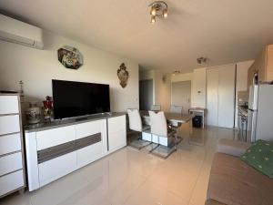 a living room with a television and a dining table at A 150m de la plage - Coquet appartement pour 4 personnes in Vias