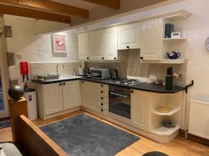 a kitchen with white cabinets and a stove top oven at Tredrea Annexe - Self Contained Cornish hideaway in Truro +13 photos