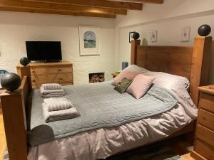 a bedroom with a wooden bed with towels on it at Tredrea Annexe - Self Contained Cornish hideaway in Truro