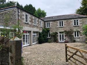 an old stone building with white doors and a bench at Tredrea Annexe - Self Contained Cornish hideaway in Truro