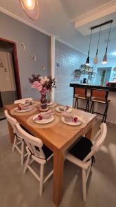 a wooden table with white chairs and a dining room at Casa piscina privativa e Área Gourmet - Condomínio 24 hs in Araruama