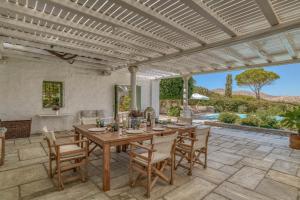 an outdoor dining room with a wooden table and chairs at Villa Thimari in Protorgia
