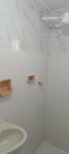 a white bathroom with a shower and a sink at Pousada Popular in Barreiras