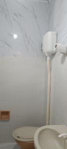a white bathroom with a toilet and a sink at Pousada Popular in Barreiras