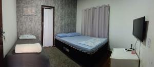 a small room with two beds and a flat screen tv at Pousada Popular in Barreiras +2 photos