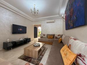a living room with a couch and a tv at Pavillon corniche Bord de mer Proche Centre in Mohammedia