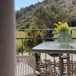a table and chairs with a vase of flowers on a balcony at Stelios Studios Sougia in Sougia