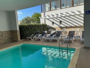 eine Gruppe von Stühlen und ein Schwimmbecken in der Unterkunft Ifestos Hotel in Mirina