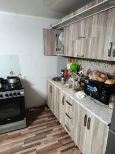 a kitchen with wooden cabinets and a stove top oven at Домик Светланы Ильиничны in Kaji-Say