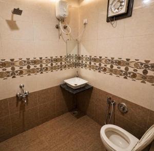 a bathroom with a toilet and a sink at Hotel Tushar in Ahmedabad