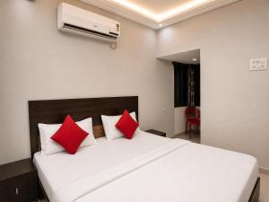 a bedroom with a white bed with red pillows at Hotel Tushar in Ahmedabad