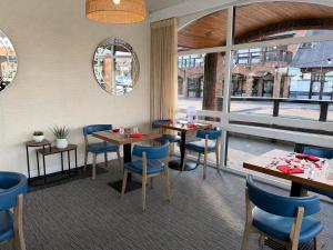 a restaurant with blue chairs and tables and windows at Boathouse Hotel in Hythe