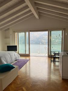 a bedroom with a bed and a table and a balcony at Dream View Lake Como in Carate Urio