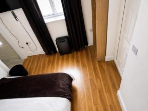 a bedroom with a bed and a wooden floor at Corner Lodge in Eltham