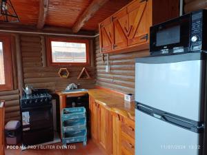 a kitchen in a log cabin with a refrigerator at Amphu colibri in La Falda