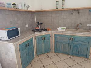 a kitchen with blue cabinets and a microwave at Sole e Sale in Sardegna in Pula +121 photos