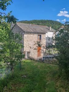 an old stone house with a orange door on a hill at L'Oursonnière de la Rende in Quérigut