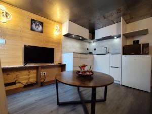a kitchen with a table and a refrigerator and a television at L'instant parental in Ustou