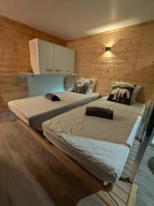 two beds in a room with wooden walls at L'instant parental in Ustou