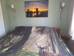 a bedroom with a bed with a painting of a deer on it at Happy Place is een modern en comfortabel chalet met een grote afgesloten tuin op de Veluwe, Recreatiepark De oude Driest in Putten