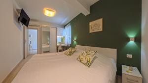 a bedroom with a white bed with a green wall at Villa Porto in Mlini