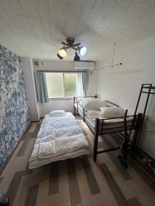 a bedroom with two beds and a ceiling fan at 東尋坊近く自転車無料 コンビニ目の前1ルーム貸切 in Mikuni