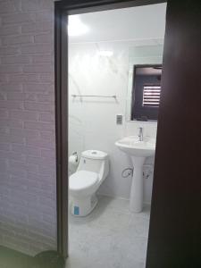 a white bathroom with a toilet and a sink at Hacienda Rosarito in Rosarito Beach