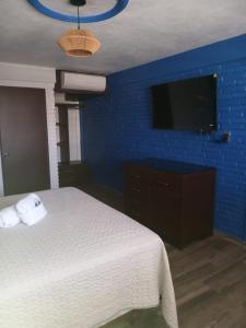 a bedroom with a white bed and a blue wall at Hacienda Rosarito in Rosarito Beach