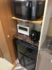 a microwave and a toaster oven on a shelf at 東尋坊近く自転車無料 コンビニ目の前1ルーム貸切 in Mikuni