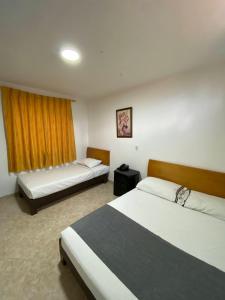 a hotel room with two beds and a window at Hotel Gran Imperio la 69 in Medellín