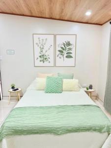 a bedroom with a large white bed with green sheets at Apartamento H González #12 in Alajuela +4 photos