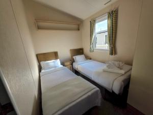 two beds in a small room with a window at Merryfield and Sandfields in Chapel Saint Leonards