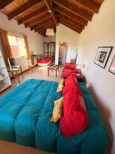 a bedroom with a large blue bed with red pillows at La Candelaria - Casas de Campo - in Sierra de la Ventana