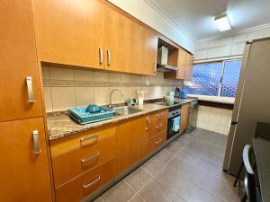 a kitchen with wooden cabinets and a sink at Teleferico Center Funchal in Funchal