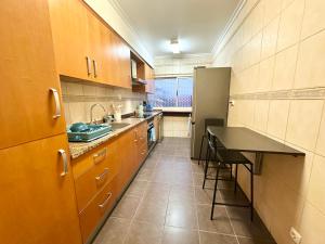 a large kitchen with wooden cabinets and a black counter at Teleferico Center Funchal in Funchal