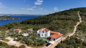 an aerial view of a house on a hill next to the water at Costa apartment with private pool in Preko